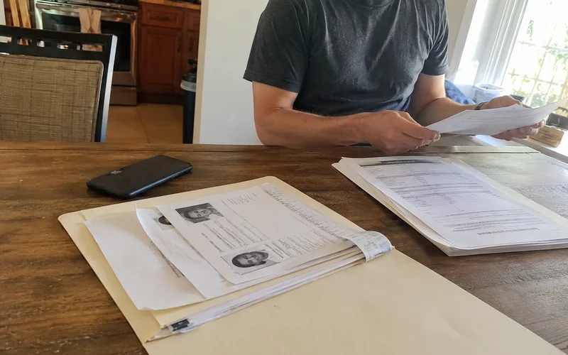 Document folder with ID, pay stubs, and court paperwork laid out on a kitchen table