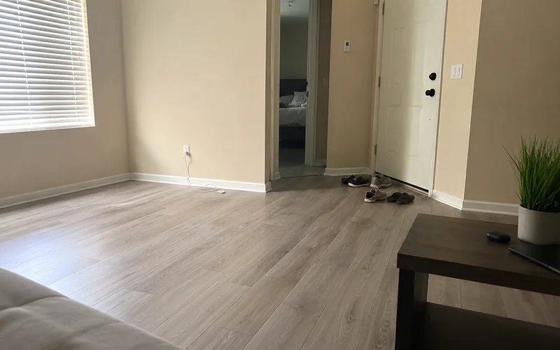 Empty apartment living room with vinyl plank flooring, white blinds, and beige walls