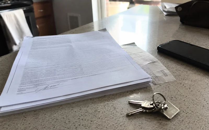 Signed lease packet and a set of apartment keys on a laminate countertop