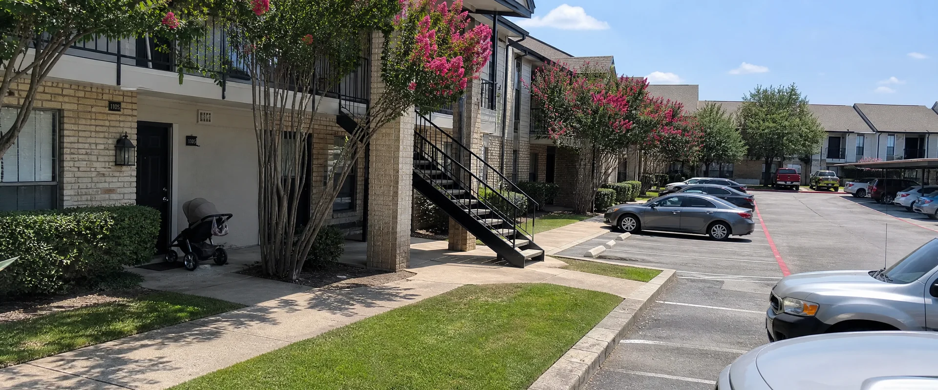 Fort Worth apartment breezeway stairs with painted metal handrails against a red brick wall