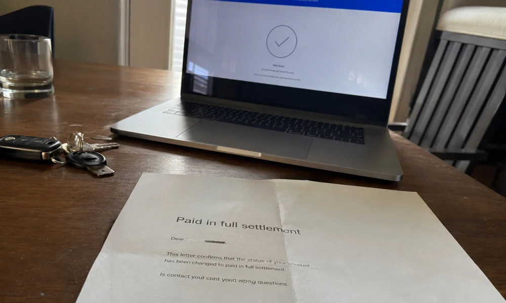 Paid-in-full settlement letter from a Tarrant County landlord on a desk beside a laptop