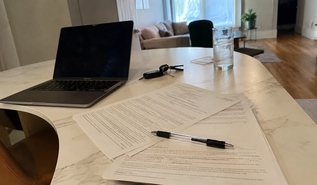 Fort Worth Second Chance Team lease paperwork and pen on a leasing office table beside a laptop